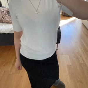 Vit kortärmad topp från Zara - En stilren vit topp från Zara med rund halsringning och korta ärmar. Modellen är figurnära och har ribbade avslut vid ärmslut och nederkant. Tillverkad i en mjuk blandning av viskos och nylon med lite stretch för en bekväm passform.