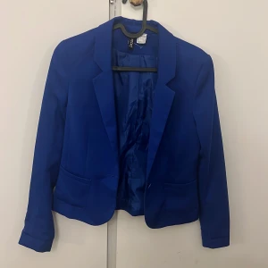 Kavaj - Säljer en klassisk och elegant blå kavaj från H&M i storlek 34. Passar perfekt både till vardag och fest – lika snygg över en blus på jobbet som till jeans för en mer avslappnad look.