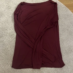 Vinröd långärmad topp - En enkel och stilren vinröd långärmad topp i mjukt och tunt material. Toppen har rund halsringning och en tight passform som passar perfekt till jeans eller kjol. Perfekt för dig som gillar minimalistisk stil och vill ha en bas i garderoben. Storlek M men sitter som S 