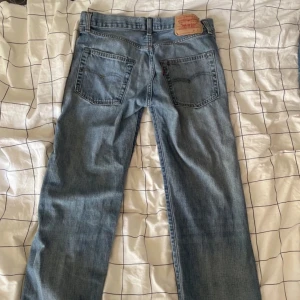 Levi's 501 Special Edition 1966 jeans - Säljer ett par Levi's 501 Special Edition 1966 jeans för kvinnor. De är ljusblå med slitna och trasiga detaljer framtill för en cool vintagekänsla. Klassisk rak passform, fem fickor och ikonisk läderpatch bak. Cool gylf också