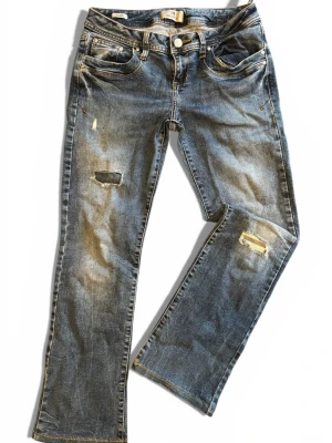 Blå bootcut jeans från LTB - Säljer ett par blå jeans från LTB med bootcut passform. Jeansen har slitna detaljer och hål på benen för en cool, avslappnad look. Klassisk femficksmodell med kontrastsömmar och normal midja. Tillverkade i tåligt denimtyg. Defekt: en bälteshälla har gått upp, går att sy fast om man är händig 😄