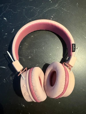 Exibel Over-Ear Hörlurar Rosa - Bekväma over-ear hörlurar från Exibel i rosa färg. Mjuka öronkuddar och justerbart huvudband för optimal komfort. Hörlurarna är i gott skick med minimalt slitage och passar perfekt för både musik och samtal. Kabelanslutning för enkel användning.