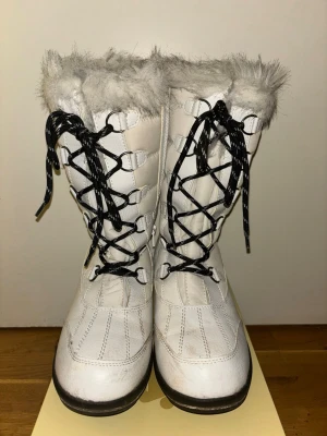 Vita vinterstövlar Everest strl 38 -  Vitq vinterstövlar från Everest i storlek 38. Skorna har svart snörning, dragkedja på sidan och fluffig grå fuskpäls upptill. Ovandelen är quiltad och sulan är rejält mönstrad för bra grepp. Perfekta för kalla dagar ❄️👢