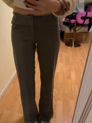 Lågmidjade gråa kostymbyxor  - Säljer ett par grå kostymbyxor från H&M i storlek 158. Byxorna har tunna vita ränder, låg midja och raka ben. Midjan är justerbar och säljer för att jag inte använder de!💗
