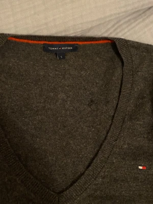 Mörkgrå v-ringad tröja Tommy Hilfiger - Mörkgrå  tröja från Tommy Hilfiger. Köpt den här för 300kr, själv har aldrig använt den, ser inga synlig skador. skriv om ni undrar om något 💕