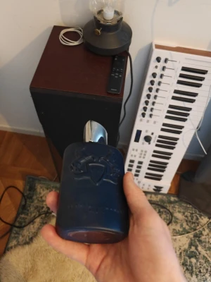 Elegant blå parfymflaska - Snygg och lyxig parfym från Parfums de Marly. Flaskan har en modern design med blått glas och silverdetaljer. Volymen är 125 ml och den är tillverkad i Frankrike. Perfekt för dig som vill sticka ut med stil.