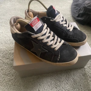 Golden goose  - Säljer ett par Golden Goose sneakers i mocka och mörkblå. Storlek 41 sitter som 42. Skorna är väl använda och har defekter på sulan (syns i bild 3) därav det låga priset.