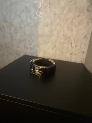 Pampiano bälte i blått och beige - Säljer ett snyggt bälte med coolt geometriskt mönster i blått, beige och brunt. Bältet har klassiskt spänne i metall och är tillverkat i skinn med broderade detaljer. Perfekt för att lyfta vilken outfit som helst! Har aldrig använts för att det var för stort för mig personligen. Kan vara villig att sänka priset vid snabb affär!