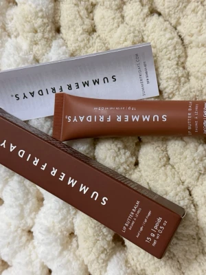 Summer Fridays Lip Butter Balm Café Frappé - Lip Butter Balm från Summer Fridays i färgen Café Frappé. Kommer i en snygg brun tub på 15g med vit text. Ger läpparna en mjuk och återfuktad känsla med en hint av färg och glossig finish. Perfekt att ha i väskan för återfuktade läppar hela dagen.