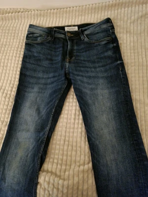 Blå jeans från Stock & Hank - Säljer ett par klassiska blå jeans från Stock & Hank. De har fem fickor, snygga slitningar och kontrastsömmar. Jeansen har normal passform och raka ben, tillverkade i slitstarkt denimtyg. Perfekta till sneakers eller boots.