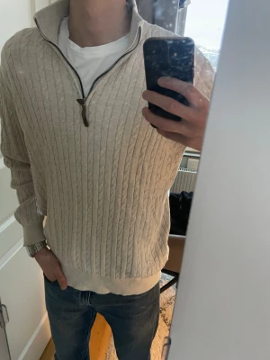 Beige stickad half zip tröja Lindbergh - Säljer en beige stickad tröja från Lindbergh i storlek M. Tröjan har ett klassiskt kabelstickat mönster, half zip-dragkedja och hög krage. Relaxed fit för skön passform och långa ärmar. Perfekt för dig som gillar stilren och enkel design. Priset kan diskuteras, hör gärna av dig om du har några frågor! Har testat tröjan en gång annars är den som ny 