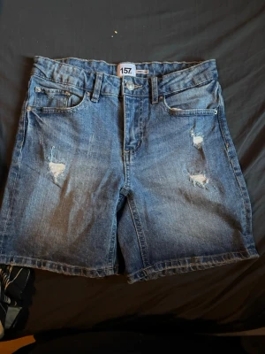 Säljer ett par korta jeansshorts från lager 157 - Tjena säljer ett par korta jeansshorts från lager 157, storlek 160 man kan spänna åt dem också, tror inte dem är använda jätte många gånger. Inga hål eller märken. Pris kan diskuteras