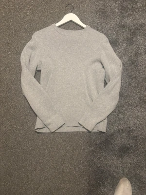 Grå stickad tröja från Jack & Jones - Säljer en enkel och stilren grå stickad tröja från Jack & Jones. Tröjan har rund halsringning och långa ärmar, perfekt för lager-på-lager under kyliga dagar. Passar dig som gillar en klassisk look med en modern touch. Storlek 164 skick 9-10