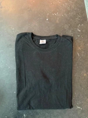 Svart basic t-shirt från B&C - En klassisk svart t-shirt från B&C med rund hals och enkel design. Perfekt till alla outfits och lätt att matcha. Tillverkad i mjuk bomull för skön känsla hela dagen.