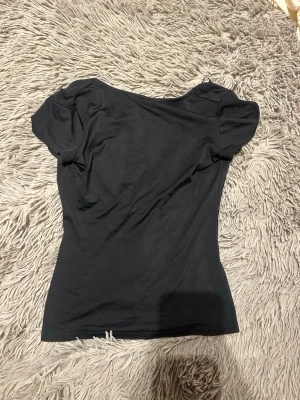 Svart topp med öppen rygg - Snygg svart topp/t-shirt med öppen rygg. Knabbt använd