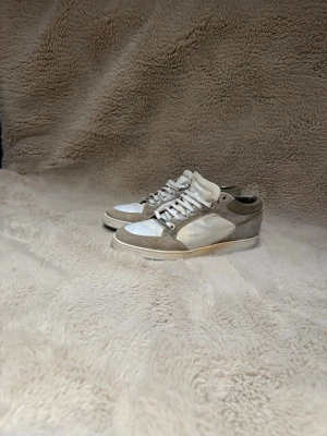 Jimmy Choo - Snygga sneakers i beige och vitt med paneler i mocka och textil. Skorna har klassisk snörning och platt sula. Perfekta för dig som gillar en clean och stilren look till vardagsoutfiten.