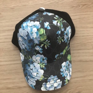 Gucci keps med blått blommönster - Snygg keps från Gucci med svart bas och blått blommönster. En väldigt bra sommarkeps passar till allt. Har tyvärr ingen box eller nått. Men priset är inte hugget i sten. Ganska ovanlig keps av Gucci 