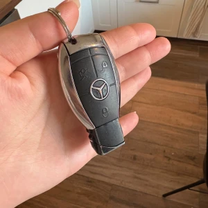 Mercedes-Benz nyckelring tändare  - Snygg nyckelring från Mercedes-Benz i svart och silverfärgad metall med klassisk logotyp. Det är en tändare Perfekt accessoar för dig som gillar bilar och vill ha något exklusivt på nyckelknippan. Den är tom på gas men kan fyllas