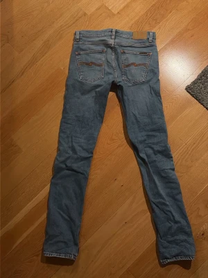 Ljusblå  jeans från Nudie - Säljer ett par ljusblå  jeans från Nudie med klassiska fickor och snygga sömmar på bakfickorna. Modellen är Lean Dean i storlek 30:34