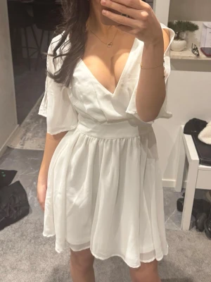 Vit studentklänning med v-ringning - Snygg vit studentklänning/sommarklänning från bubbleroom med V-ringning och knytdetalj bak. Klänningen är aldrig använd, endast testad. Nypris: 799. Säljer för 599, men pris kan diskuteras vid snabb affär💞