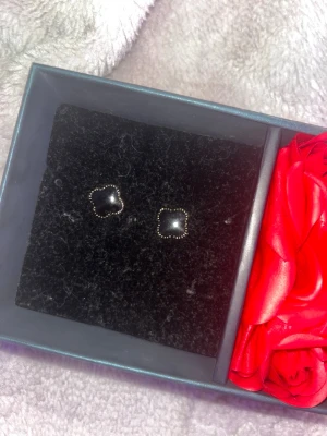 Svarta fyrklöver örhängen med guldkant - Snygga örhängen i form av små svarta fyrklöver med en tunn guldfärgad kant. Perfekta för dig som gillar stilrena och trendiga accessoarer. Kommer i en fin ask.