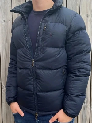Mörkblå puffer från Ralph Lauren .🙌🤩 - Snygg mörkblå dunjacka från Ralph Lauren med quiltad design och hög krage. Jackan har dragkedja framtill, två sidofickor med dragkedja och en bröstficka. Perfekt för kalla dagar och ger en modern, sportig look.🙌🤩