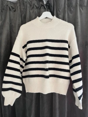 Stickad tröja  - Säljer en stickad tröja i offwhite med svarta horisontella ränder. Tröjan har en avslappnad passform, rund halsringning och ribbade muddar vid ärmslut och nederkant. Perfekt för en chill och trendig look. Använd nån enstaka gång! 💕