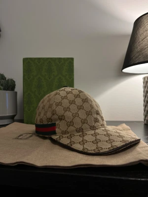 Gucci keps beige  - Säljer en beige Gucci keps med klassiskt GG-monogram. Låda & Dustbag följer ej med!