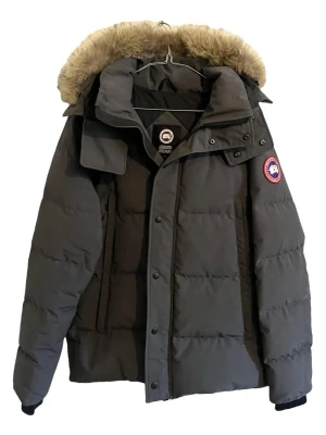 Grå dunjacka från Canada Goose - Snygg grå dunjacka från Canada Goose med pälskantad huva och klassisk logga på ärmen. Jackan har quiltad design, dragkedja och knappar framtill samt långa ärmar. Perfekt för kalla dagar och riktigt varm. Köpt begagnad för 8000kr. Har valt att sälja den för 4000kr för att köpa en lite billigare jacka. Kan diskutera pris i dm.