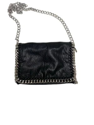 Svart väska med kedja - Säljer en snygg svart väska ifrån tiamo i skinnimitation med grov silverfärgad kedja som axelband och detaljer runt kanterna. Väskan har dragkedja baktill och en cool, lite slouchy form. Mycket gott skick! Tveka inte att höra av dig vid frågor!!