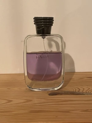 Rasasi hawas 70 ml - Stilren parfym från rasasi  i en rektangulär glasflaska med lila vätska. Flaskan har en grå, räfflad kork och minimalistisk design som känns modern och elegant. Perfekt för dig som gillar exklusiva dofter och snygg inredningsdetalj på hyllan.