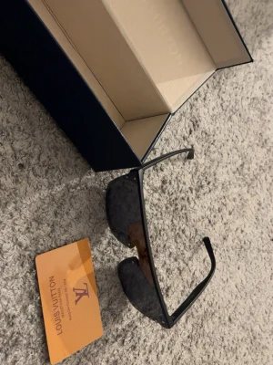 solglasögon - Säljer ett par solglasögon med spegelglas och monogrammönster. Svarta plastbågar med shield-form.  Solglasögonen är i fint skick. Originalbox, fodral/skydd och kvitto (kortformat) medföljer.  Alla bilder är egna och visar exakt vad som ingår. Se bilder för detaljer och egen bedömning.