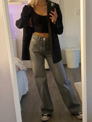 Gråa Zara jeans - Säljer ett par gråa jeans med hög midja och wide fit. Klassisk femficksmodell i slitstark bomullsdenim. Jeansen har raka ben och en snygg vintagekänsla som passar perfekt till sneakers eller boots.