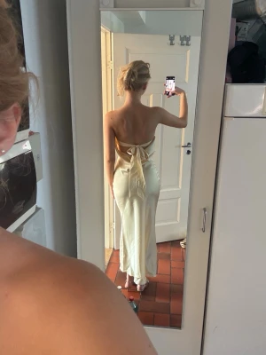 Ljusgul satinklänning - Superfin ljusgul satinklänning som är perfekt för festliga tillfällen så som bal exempelvis!💕 den är helt ny och har därmed inga defekter. Den har ett band i ryggen (bild 3) som man kan justera efter sina egna mått och därmed passar den flera storlekar! Jag är 175 cm lång och har klackar på mig på alla bilder❣️ först till kvarn! 
