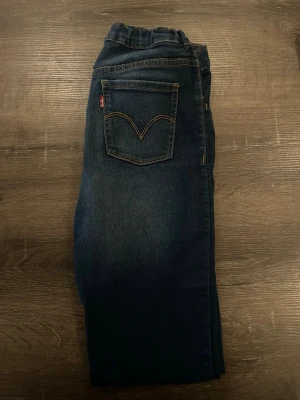 Levi's mörkblå skinny jeans - Mörkblå skinny jeans från Levi's med klassisk femficksdesign och gul kontrastsöm. Jeansen har en smal passform och är tillverkade i mjukt denimtyg. Perfekta för en clean och stilren look.