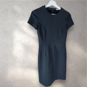  kort klänning från Filippa K - Snygg grå klänning från Filippa K med rund halsringning och korta ärmar. Modellen är figurnära med markerad midja och har en diskret dragkedja i ryggen. #klänning #filippaK
