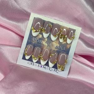 FrenchGold (M);Medium Almond - Snygga handgjorda press-on naglar i nude med vit handmålade franska tippar, dekorerade med små guldpärlor och 3D-rosetter i guld. Naglarna har en elegant form och passar dig som vill ha en lyxig och trendig look. Perfekt för dig som gillar detaljer och vill sticka ut.M: 16 mm, 12 mm, 12,5 mm, 11,5 mm, 10 mm