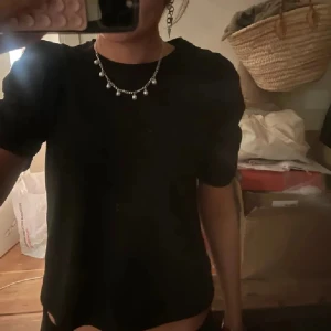 Svart t-shirt med puffärmar  - En svart, klassisk t-shirt med rund hals och korta ärmar men även puffärmar på båda sidorna. Perfekt basplagg men även också festlig av sig, tröjan funkar till allt och är lätt att styla med smycken. T-shirten har en rak passform och är tillverkad i ett mjukt material.