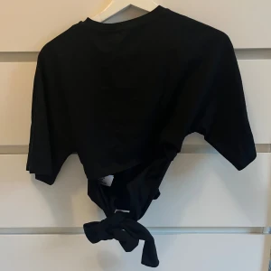 Tröja med öppen rygg knytbar rygg  - Svart i storlek xs. Kortare ärmar med öppen rygg och med knyte i ryggen 