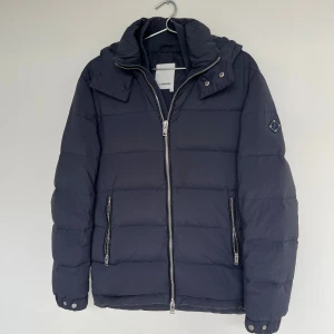 Mörkblå pufferjacka från J.Lindeberg - Riktigt fet jlindberg jacka i fint skick! Storlek M. Modellen är ca 180. Kontakta mig för fler frågor och funderingar!