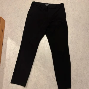 Svart kostym byxor  - Snygga svarta kostymbyxor från H&M med smal passform och klassisk design. Byxorna har bälteshällor, diskreta fickor bak och är croppade i modellen. Perfekta för dig som gillar stilrena och enkla plagg.