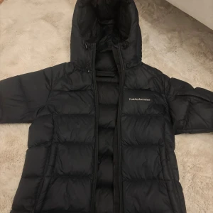 Svart Peak Performance dunjacka XS - Säljer en svart dunjacka från Peak Performance i storlek XS.Det är inga hål eller nåt vidare på jackan. Den är väldigt varm och håller kylan i vinter. Den är i jätte bra skick och normal priset är 2700kr