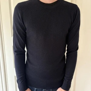 Svart stickad tröja från Matinique  - En marinblå stickad tröja från Matinique. Tröjan har rund halsringning, diskret strukturmönster framtill och ribbade muddar vid ärmslut och nederkant. Perfekt för lager-på-lager och enkel att matcha med jeans. Storleken är XS men passar som S.                                                                  Tröjan har ett litet hål men inget man tänker på.                                                  Pris kan diskuteras!