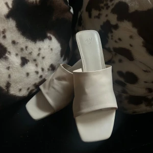 Vita sandaler med klack/klackskor från H&M - Stilrena vita klackskor/sandaler från H&M med fyrkantig tå och låg klack. Skorna är de absolut skönaste jag burit! De är enbart använda 1 gång, har bred rem över foten och är tillverkade i ett mjukt syntetmaterial. Perfekta för dig som gillar minimalistisk och trendig design. Skorna är helt slutsålda, och inhandlades för 400 or men jag säljer de för billigare!💕