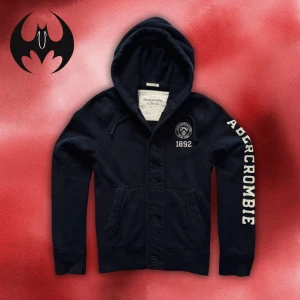 Svart hoodie cardigan från Abercrombie & Fitch  - Svart hoodie cardigan från Abercrombie & Fitch med broderad logga och årtal 1892 på bröstet samt stor vit text längs ena ärmen | size L | svår att få tag på och limiterad | Längd: 68cm Axelbredd: 54cm Armlängd: 70cm | Passar för 180-195 