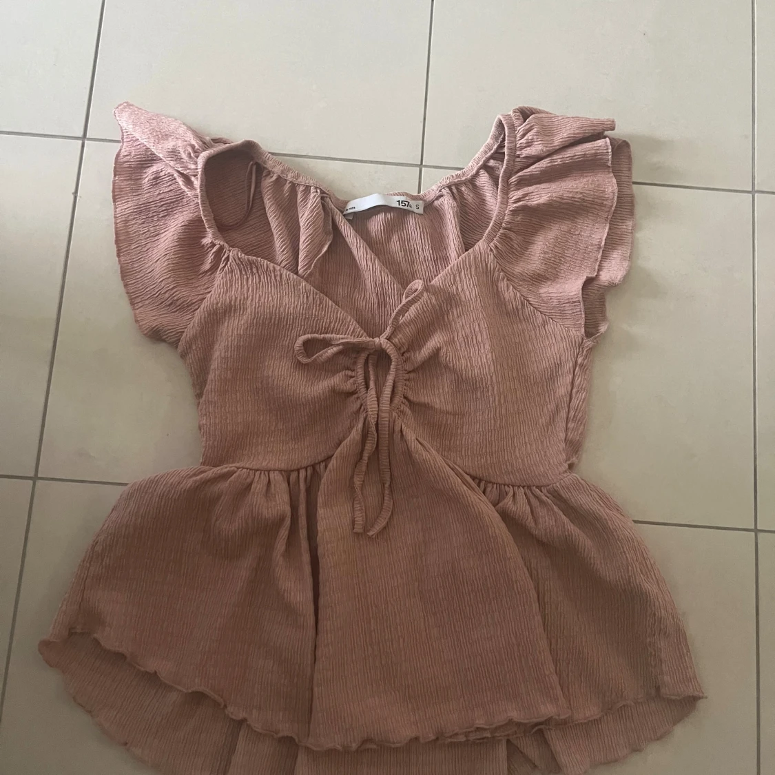 Rosa blus med volang och knyt