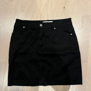 Svart jeanskjol med fickor - Snygg svart jeanskjol med klassisk många bra fickor. Stretchig och bekväm. 