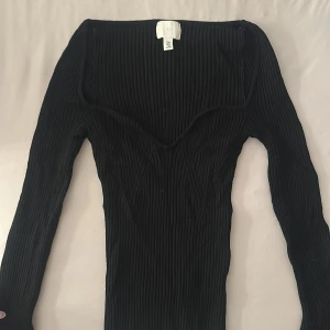 Svart ribbad långärmad tröja H&M - Snygg svart ribbad tröja från H&M med lång ärm och figurnära passform. Storlek S