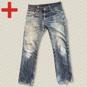 Vintage Nudie Jeans Slim Jim - Riktigt snygga vintage Nudie Slim Jim med otrolig patina. Storlek 32/32. Relativt straight modell med lätt bootcut-form. Snygg whiskering och i bra skick. Några små hål vid knä och en bakficka. Mått: Midja – 41,5 cm, Innersöm – 79 cm, Yttersöm – 102 cm, Lår – 27 cm, Benöppning – 20 cm. Skriv gärna vid frågor!