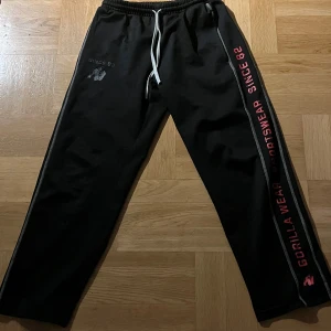 Svarta mjukisbyxor Gorilla Wear S/M - Svarta mjukisbyxor från Gorilla Wear med vit snörning i midjan och tryck längs benet.